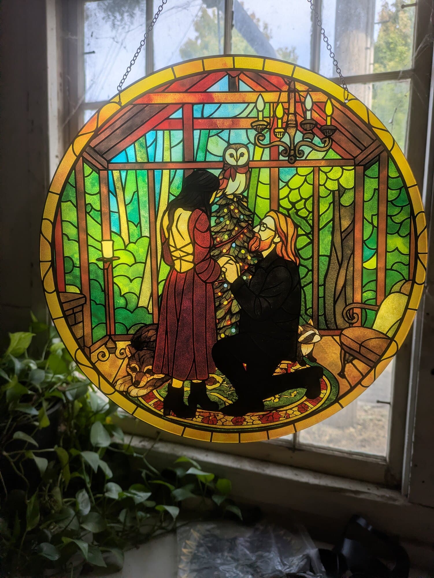 Engagement proposal reimagined as a round stained glass style suncatcher hanging in a window